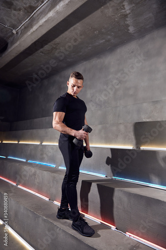 man is training with dumbbells on the background of neon lights © Katerina