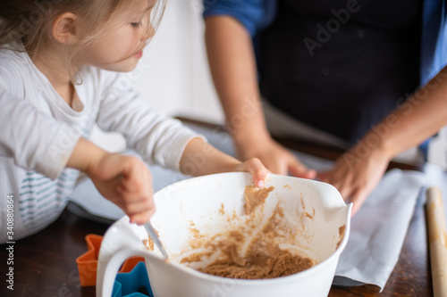 Child mixing dough and helping mother bake