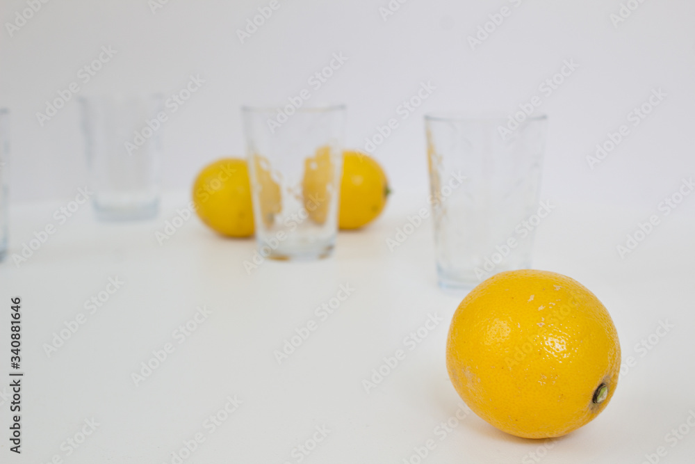 Still life with yellow lemons and glasses on white background home creative cuisine healthy food lifestyle concept Still life with yellow lemons and glasses on white background home creative cuisine healthy food lifestyle concept