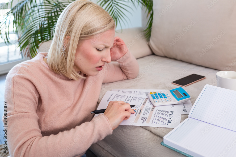 Beautiful young Albino woman sitting with calculator and bills, doing paperwork. Hand woman doing finances and calculate on desk about cost at home office.Concept work from home