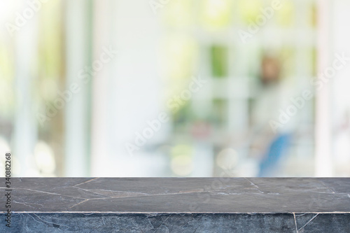 Empty black stone marble table top and blurred of interior restaurant with window view green from tree garden background background - can used for display or montage your products.