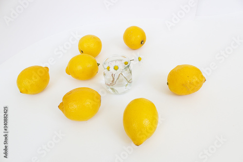 Yellow lemons with daisy flowers bouquet on white background  healthy home food and drink concept