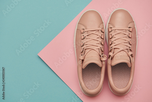 Stylish pink female shoes on pastel background, copy space. New sneakers on pink and blue background. Beauty and fashion concept. Flat lay, top view. Overhead shot