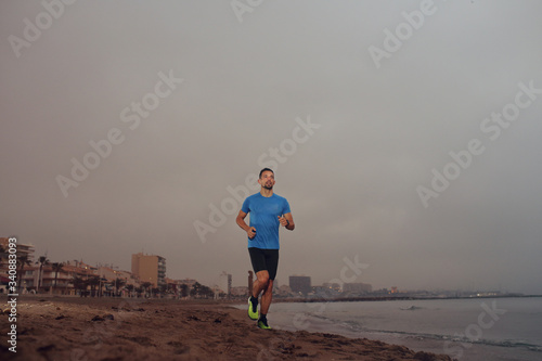 Outdoor training. A young athletic attractive man runs alone by the sea.