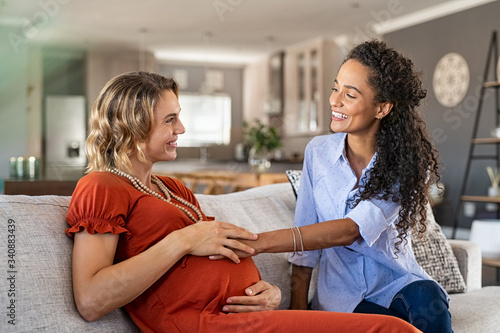 Foto Excited friend touching belly bump of pregnant woman