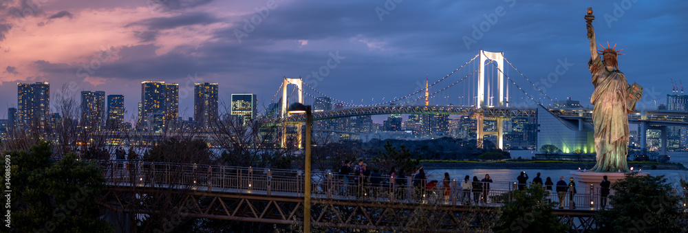 Fototapeta premium Undefined tourist seesighting on the bridge with Statue of Liberty and Rainbow bridge, located at Odaiba Tokyo, Japan
