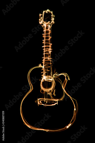 glowing orange outline of an acoustic guitar on a black background. freeze light photo