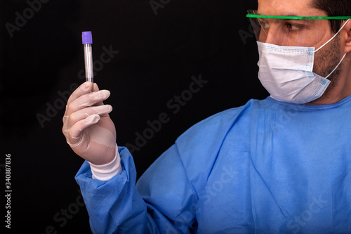 Lab doctor is holding in his hand a tube containing a swab sample that has tested positive for Covid-19. Testing for presence of coronavirus