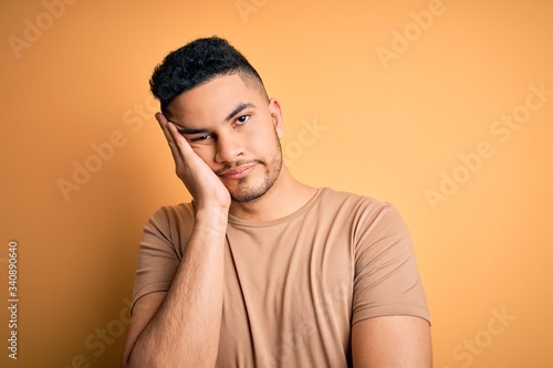 Young handsome man wearing casual t-shirt standing over isolated yellow background thinking looking tired and bored with depression problems with crossed arms. © Krakenimages.com