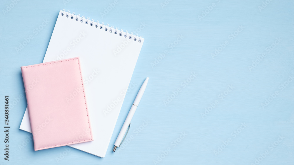 Blank notepad with pen and documents on blue background. Flat lay, top view office desk. Minimal style feminine workspace Blank notepad with pen and documents on blue background. Flat lay, top view office desk. Minimal style feminine workspace