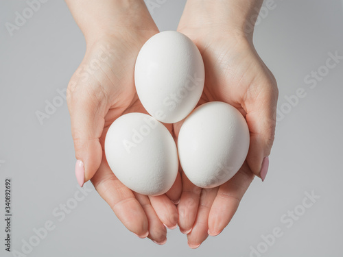 Woman hands with white eggs isolated on grey background