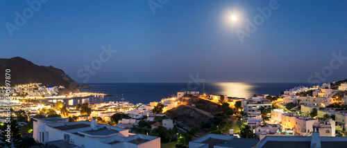 Panoramic night view of the city of San José in the Cabo de Gata Natural Park, Almeria, with the Mediterranean sea in the background and the reflection of the moon.