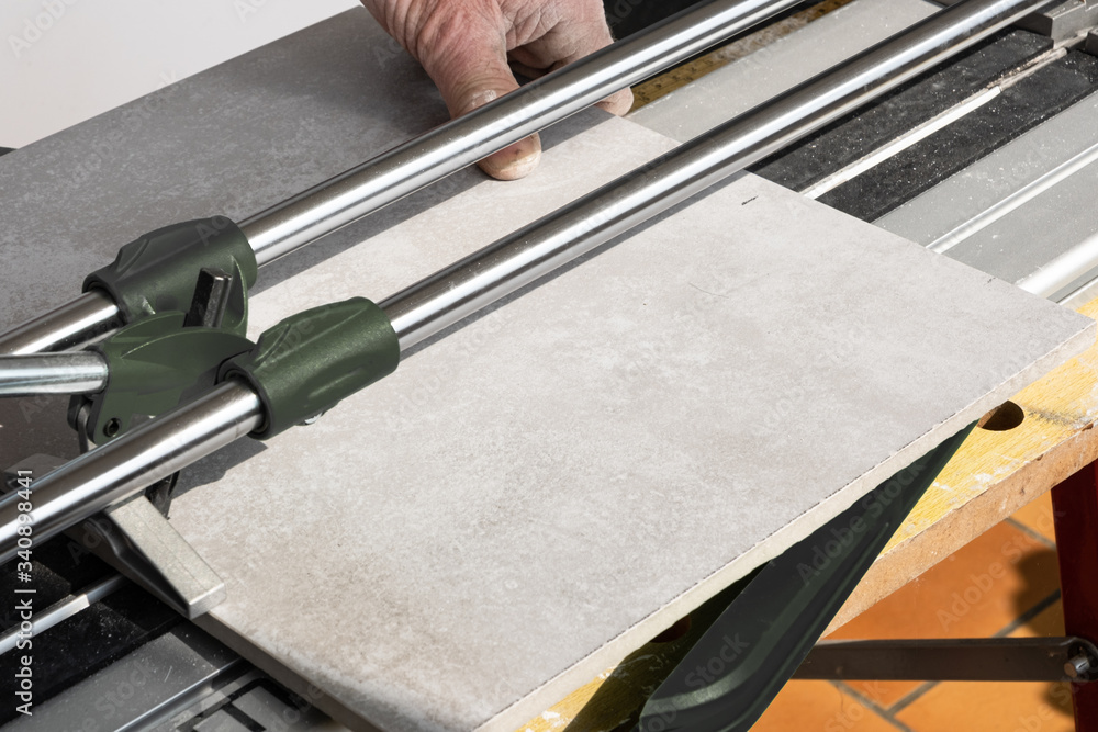 the mason cuts a ceramic tile with a tile cutter the mason cuts a ceramic tile with a tile cutter