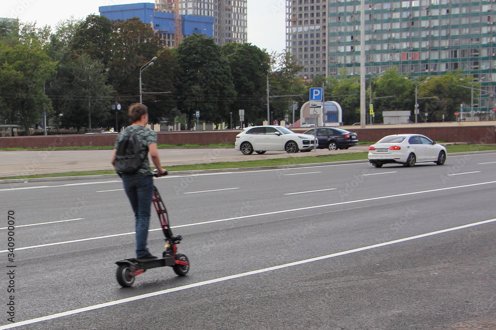 A guy on an electric scooter fast rides on a highway in the city, urban road safety kids