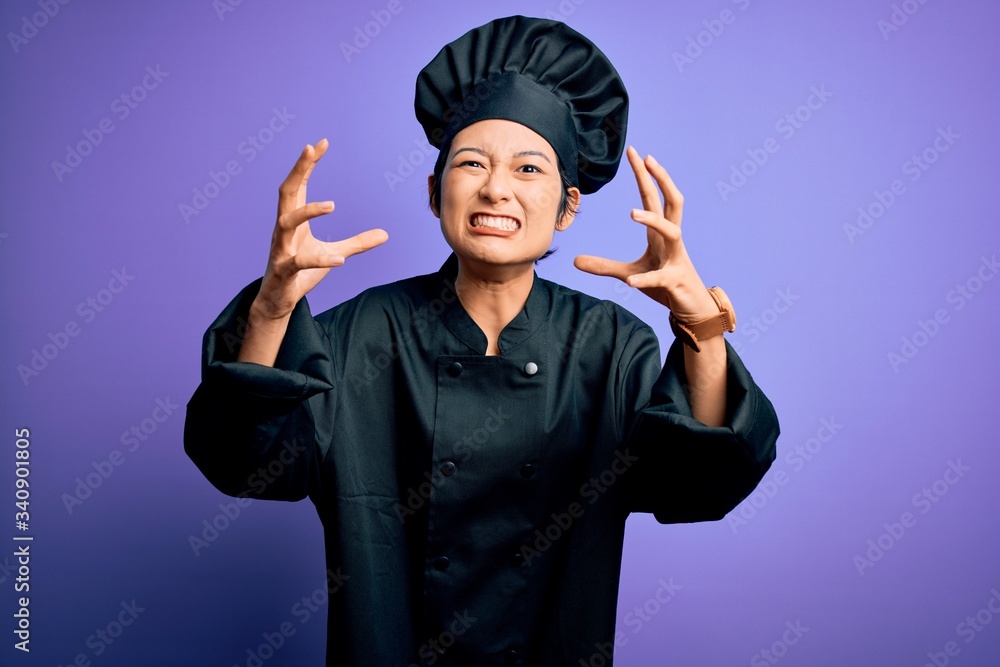 Young beautiful chinese chef woman wearing cooker uniform and hat over purple background Shouting frustrated with rage, hands trying to strangle, yelling mad Young beautiful chinese chef woman wearing cooker uniform and hat over purple background Shouting frustrated with rage, hands trying to strangle, yelling mad