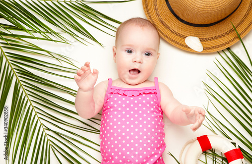 Cute baby girl with beach accessories on light background. Holidays at sea with baby, summer concept