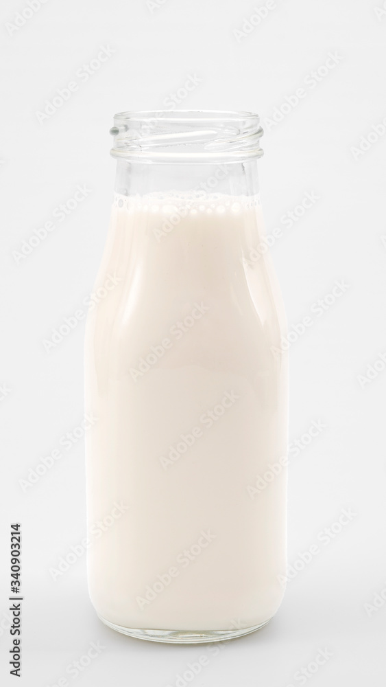 Calcium rich drink and nutritious refreshment concept with full rustic transparent glass milk bottle isolated on white background with clipping path cutout Calcium rich drink and nutritious refreshment concept with full rustic transparent glass milk bottle isolated on white background with clipping path cutout