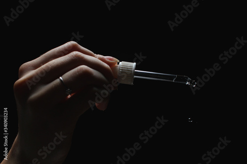 female with beautiful nails hold pipette isolated on black background