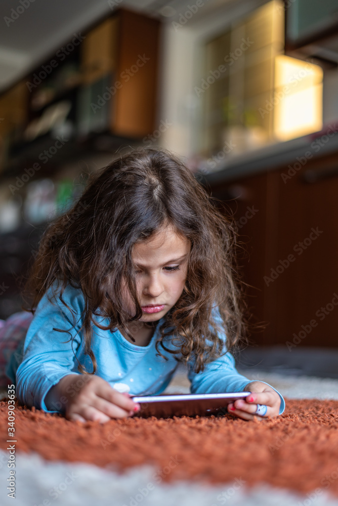 Cute little girl lying down looking at mobile Cute little girl lying down looking at mobile