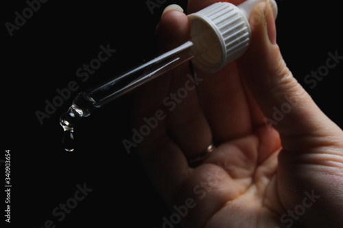 Wallpaper Mural female with beautiful nails hold pipette isolated on black background Torontodigital.ca