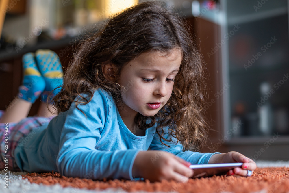 Cute little girl lying down looking at mobile Cute little girl lying down looking at mobile