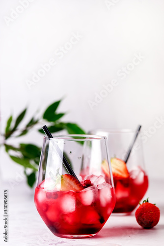 Glasses of Tasty Cranberry Cocktail with Ice Cubes on light Gray Background Alcoholic Drink Straws Vertical