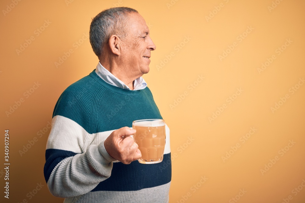 Senior handsome man drinking jar of beer standing over isolated yellow background looking to side, relax profile pose with natural face and confident smile. Senior handsome man drinking jar of beer standing over isolated yellow background looking to side, relax profile pose with natural face and confident smile.