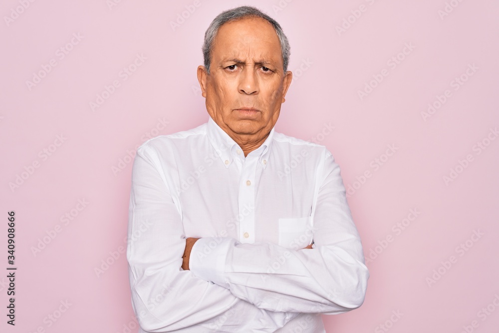 Senior handsome grey-haired man wearing elegant shirt over isolated pink background skeptic and nervous, disapproving expression on face with crossed arms. Negative person. Senior handsome grey-haired man wearing elegant shirt over isolated pink background skeptic and nervous, disapproving expression on face with crossed arms. Negative person.