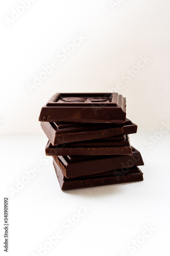 Pieces of delicious milk chocolate on a white plate, side view