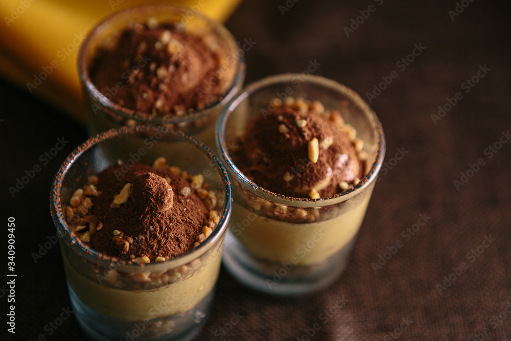Detail of three dessert glasses with coffee cream and cocoa. On dark background Detail of three dessert glasses with coffee cream and cocoa. On dark background