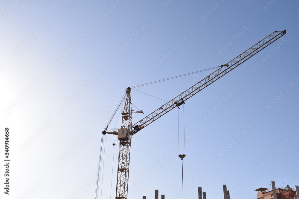 Industrial construction building crane against cloudy sunset sky in background Industrial construction building crane against cloudy sunset sky in background