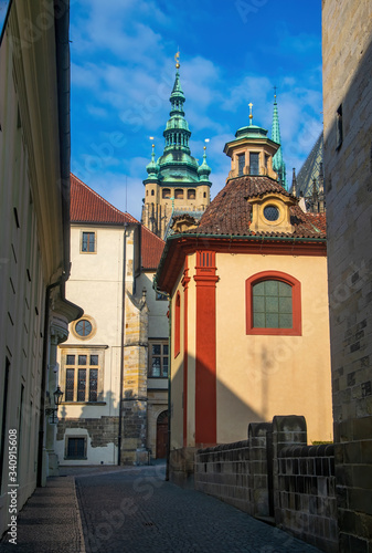 Empty narrow street in Prague castle. Chapel of John of Nepomuk and tower of St. Vitus Cathedral on background, Prague