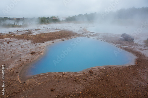 Blue lake in hot springs with fog at Geysir Iceland
