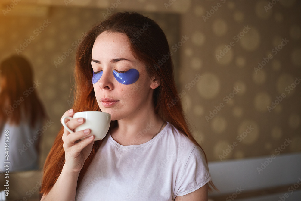 Young attractive woman with mask under eyes drinking coffee. Beautiful female with natural makeup, have collagen patches on fresh facial skin in home. Morning routine Young attractive woman with mask under eyes drinking coffee. Beautiful female with natural makeup, have collagen patches on fresh facial skin in home. Morning routine