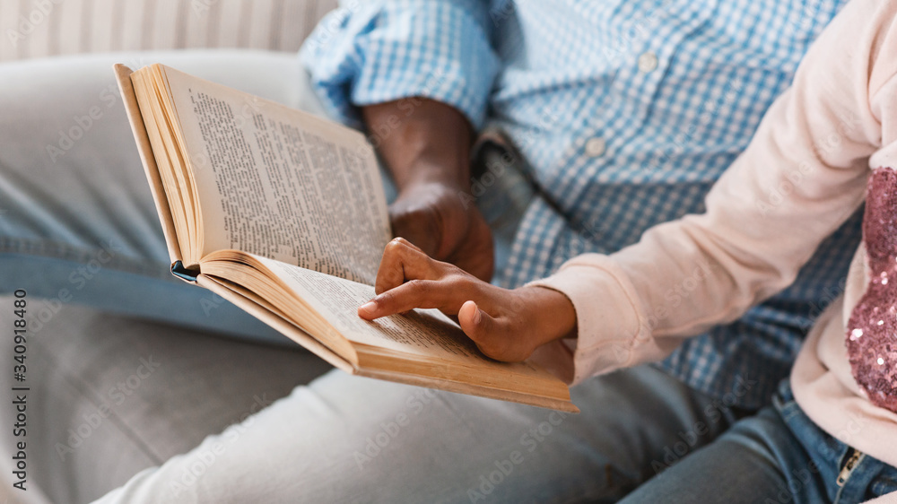 Stay home activities. Lillte African American girl reading fairy tale with her granddad, close up of hands holding book Stay home activities. Lillte African American girl reading fairy tale with her granddad, close up of hands holding book