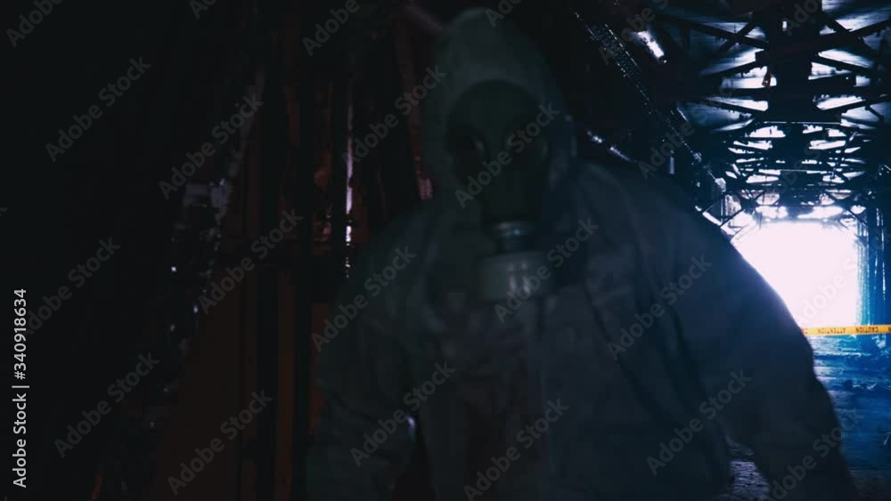 Adult In White Hazmat Suit Wearing Face Respirator Walking Down Derelict Corridor. Slow Motion, Follow Shot Adult In White Hazmat Suit Wearing Face Respirator Walking Down Derelict Corridor. Slow Motion, Follow Shot
