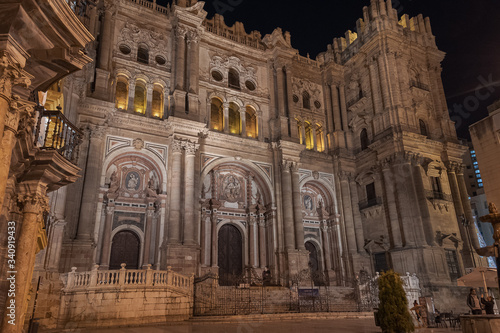Malaga Cathedral facade exterior at night front western entrance illuminated.
