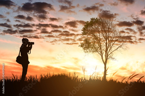 Silhouette of male photographer taking picture against sunset background.