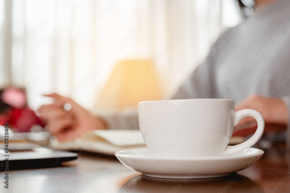 Woman work from home have a coffee cup beside wait epidemic situation to improve soon at home. Coronavirus, covid-19, Work from home (WFH), Social distancing, Quarantine, Prevent infection concept. Woman work from home have a coffee cup beside wait epidemic situation to improve soon at home. Coronavirus, covid-19, Work from home (WFH), Social distancing, Quarantine, Prevent infection concept.