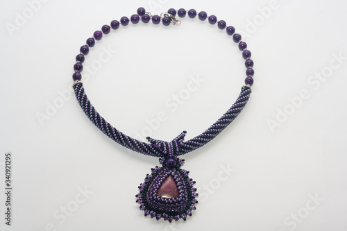 Beaded purple necklace with pendant on white background. Female accessories, decorative ornaments and jewelry. Fashion and style concept.