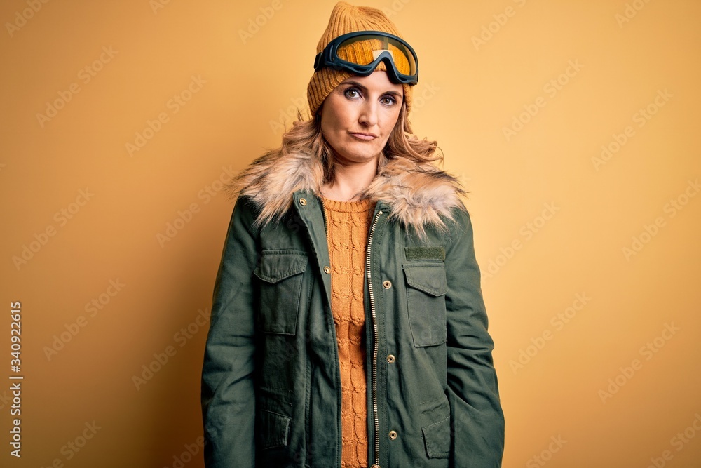 Middle age beautiful blonde skier woman wearing snow sportwear and ski goggles depressed and worry for distress, crying angry and afraid. Sad expression.