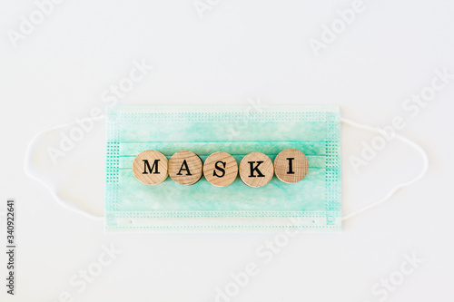 Words written with wooden blocks with black letters laying on protective surgical masks "Maski" means "masks" in polish.