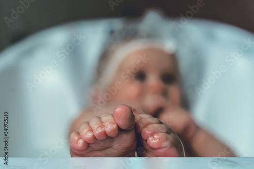 A Baby girl bathes in a bath with foam and soap bubbles. Childhood and baby care concept