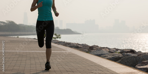 Fitness woman runner running on sunny coast trail