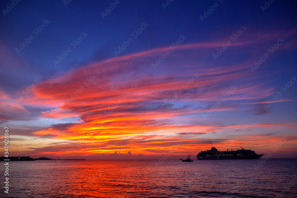 Dramatic colorful sunset with a cruise ship sailing in the Caribbean Sea