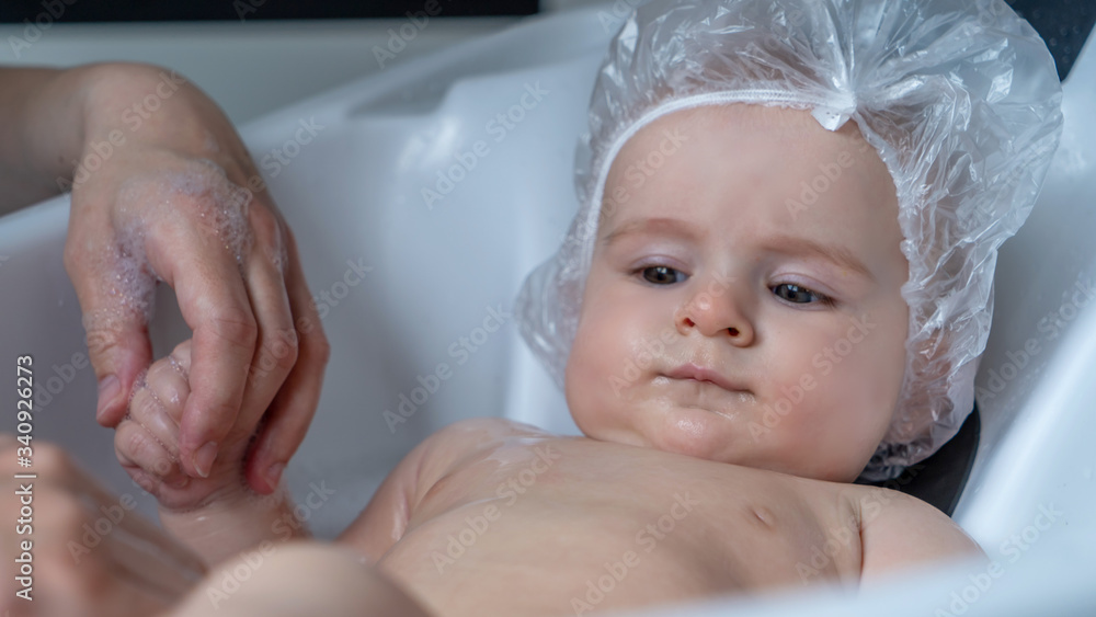 A Baby girl bathes in a bath with foam and soap bubbles. Childhood and baby care concept A Baby girl bathes in a bath with foam and soap bubbles. Childhood and baby care concept