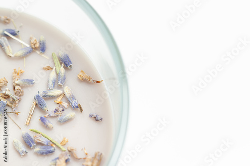 Aromatized candle with small dry lavender flowers isolated on white background
