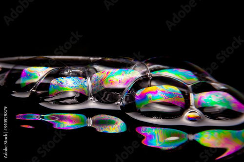 Close up of the Colorful bubbles on a black background. Refection of the Soap bubbles on the water surface on black background.