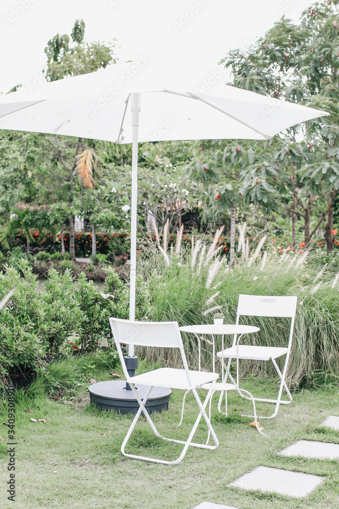 White Table,chair set and patio umbrella for relaxing with nature atmosphere in the outdoor garden the tree shade with the afternoon light.It has white color and antique style, but look a bit old. White Table,chair set and patio umbrella for relaxing with nature atmosphere in the outdoor garden the tree shade with the afternoon light.It has white color and antique style, but look a bit old.