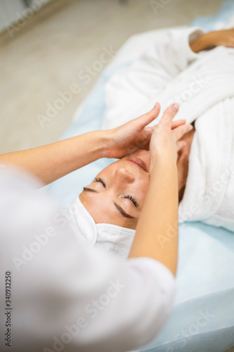 young woman during cosmetological procedure of face massage
